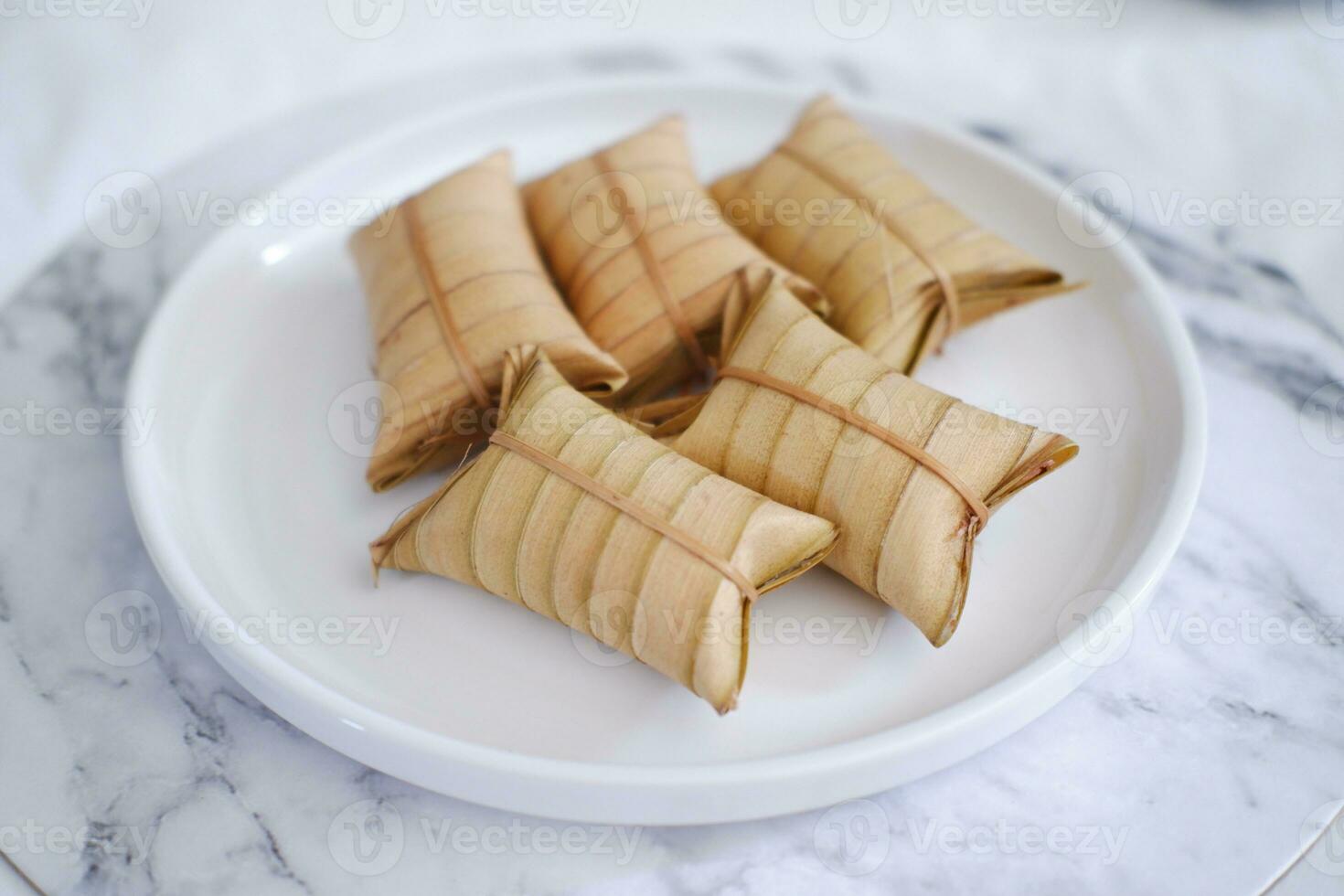 Lepet or Leupeut is a type of snack made from glutinous rice mixed with peanuts, cooked in coconut milk, then wrapped in coconut leaves. Close up view photo