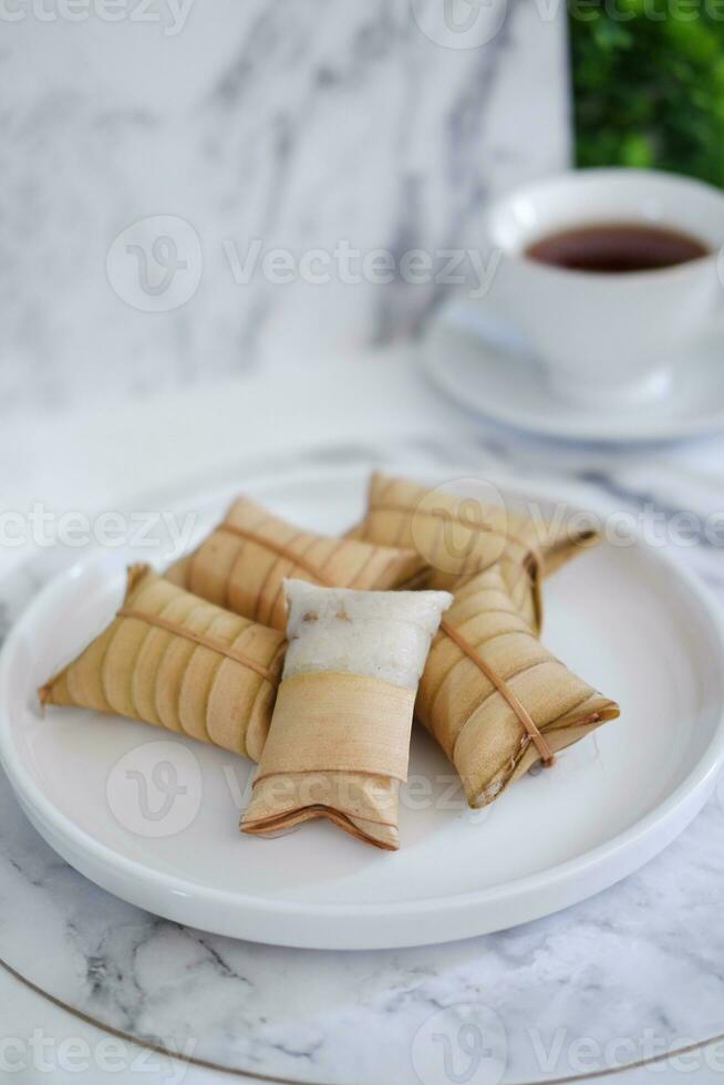 Lepet or Leupeut is a type of snack made from glutinous rice mixed with peanuts, cooked in coconut milk, then wrapped in coconut leaves. Close up view photo