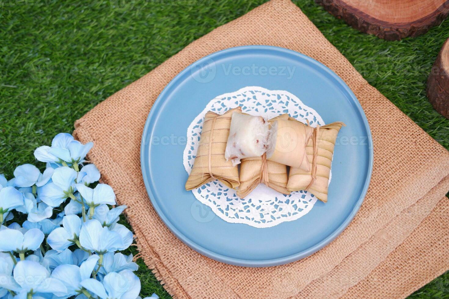 Lepet or Leupeut is a type of snack made from glutinous rice mixed with peanuts, cooked in coconut milk, then wrapped in coconut leaves. Close up view photo