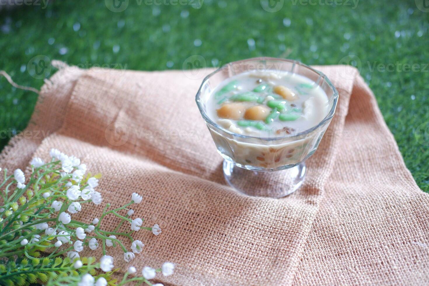 coconut milk in small glass on green grass background photo