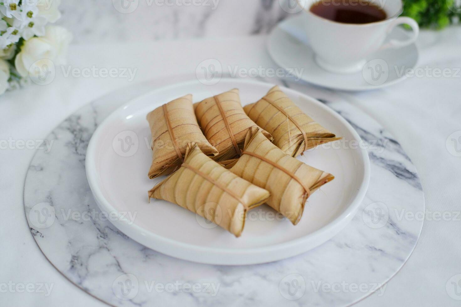 Lepet or Leupeut is a type of snack made from glutinous rice mixed with peanuts, cooked in coconut milk, then wrapped in coconut leaves. Close up view photo