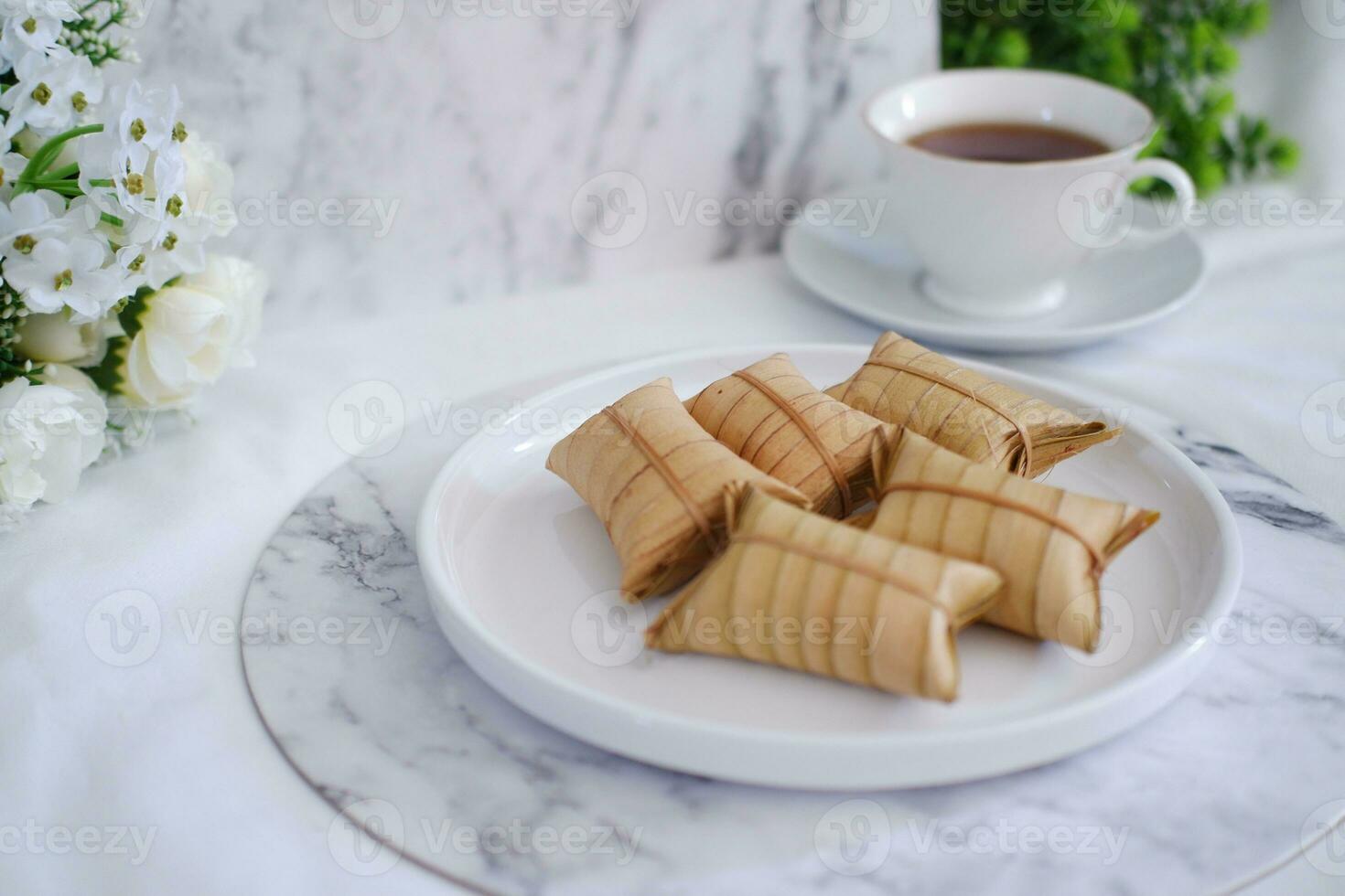Lepet or Leupeut is a type of snack made from glutinous rice mixed with peanuts, cooked in coconut milk, then wrapped in coconut leaves. Close up view photo