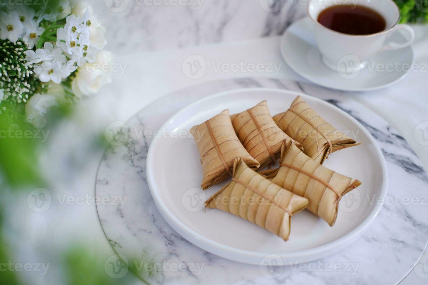 Lepet or Leupeut is a type of snack made from glutinous rice mixed with peanuts, cooked in coconut milk, then wrapped in coconut leaves. Close up view photo