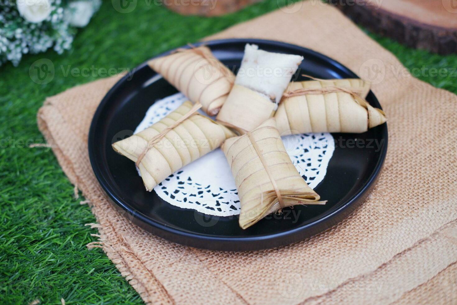 Lepet or Leupeut is a type of snack made from glutinous rice mixed with peanuts, cooked in coconut milk, then wrapped in coconut leaves. Close up view photo