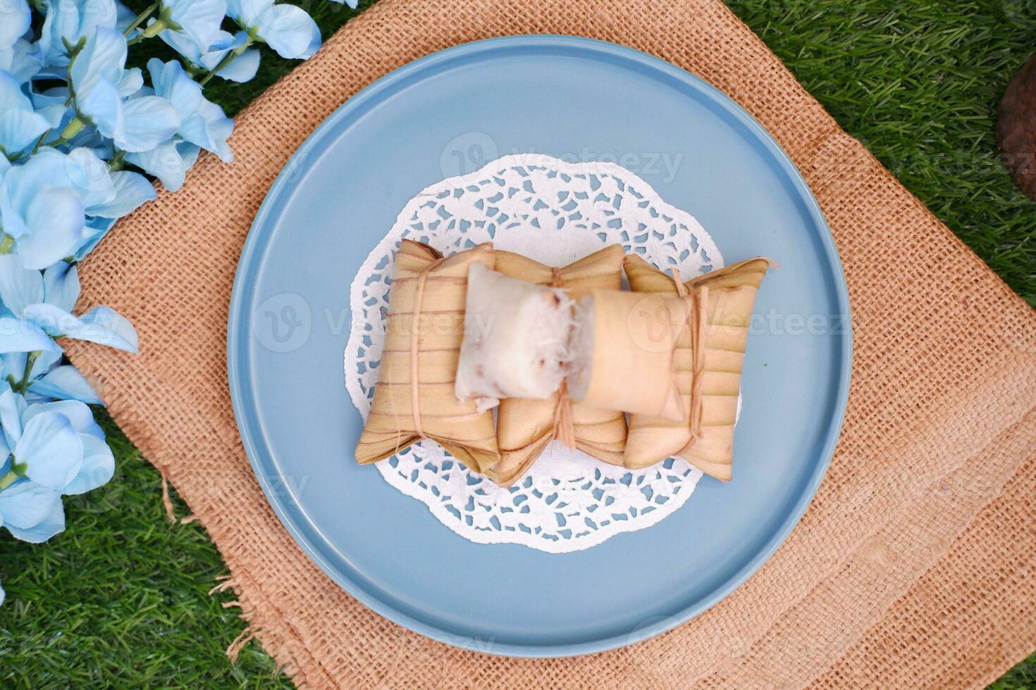 Lepet or Leupeut is a type of snack made from glutinous rice mixed with peanuts, cooked in coconut milk, then wrapped in coconut leaves. Close up view photo
