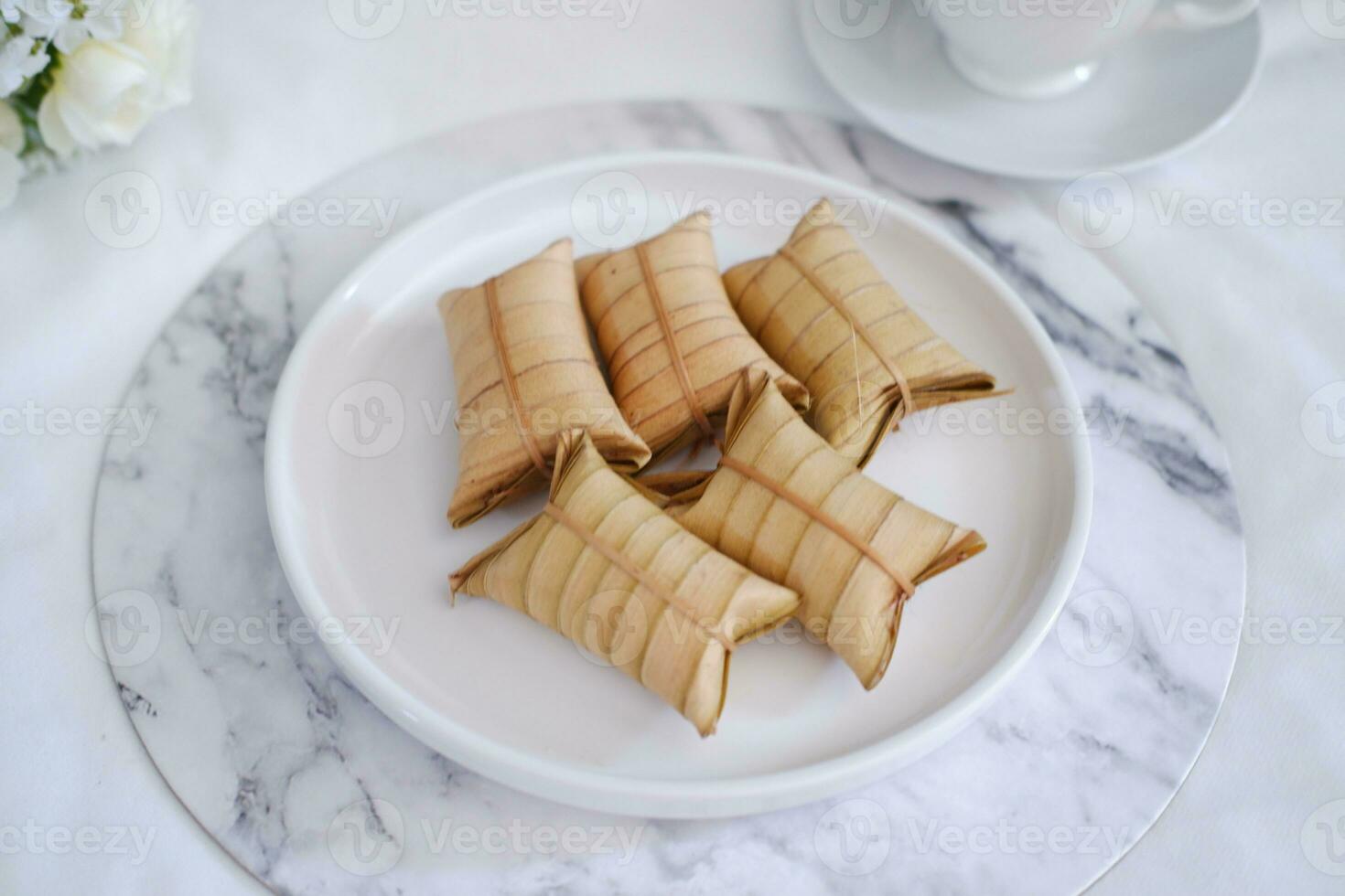 Lepet or Leupeut is a type of snack made from glutinous rice mixed with peanuts, cooked in coconut milk, then wrapped in coconut leaves. Close up view photo