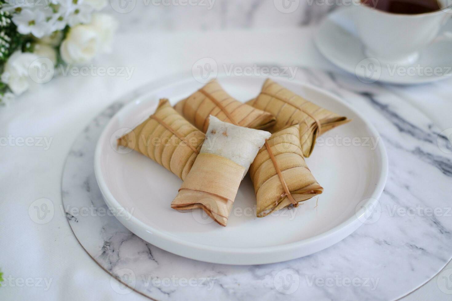Lepet or Leupeut is a type of snack made from glutinous rice mixed with peanuts, cooked in coconut milk, then wrapped in coconut leaves. Close up view photo