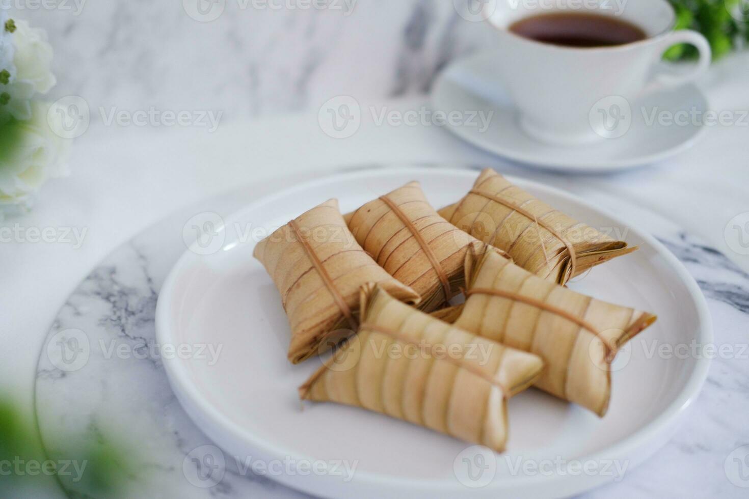 Lepet or Leupeut is a type of snack made from glutinous rice mixed with peanuts, cooked in coconut milk, then wrapped in coconut leaves. Close up view photo