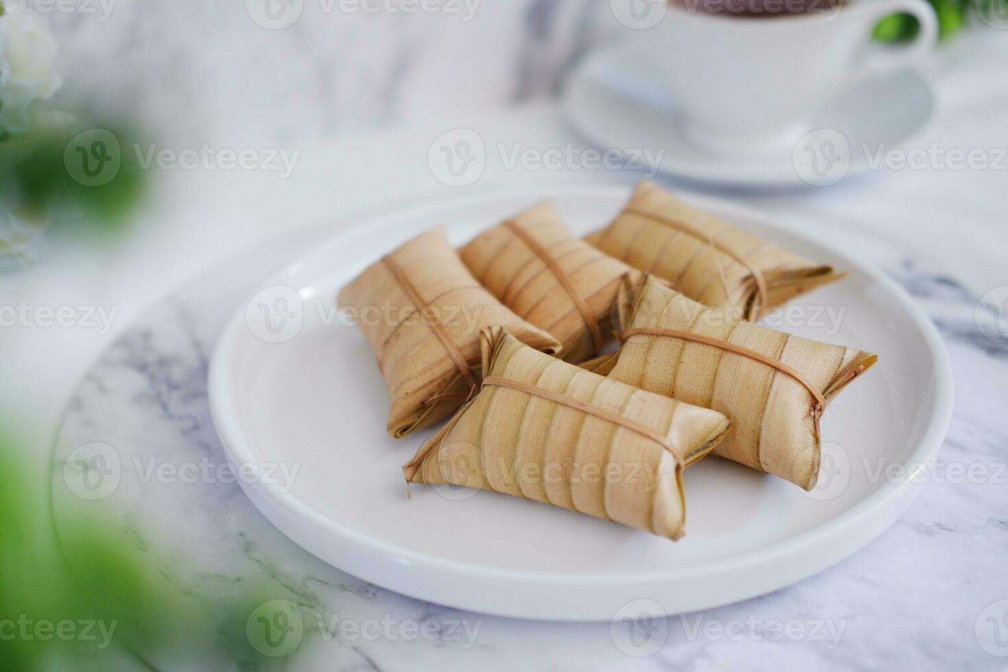 Lepet or Leupeut is a type of snack made from glutinous rice mixed with peanuts, cooked in coconut milk, then wrapped in coconut leaves. Close up view photo