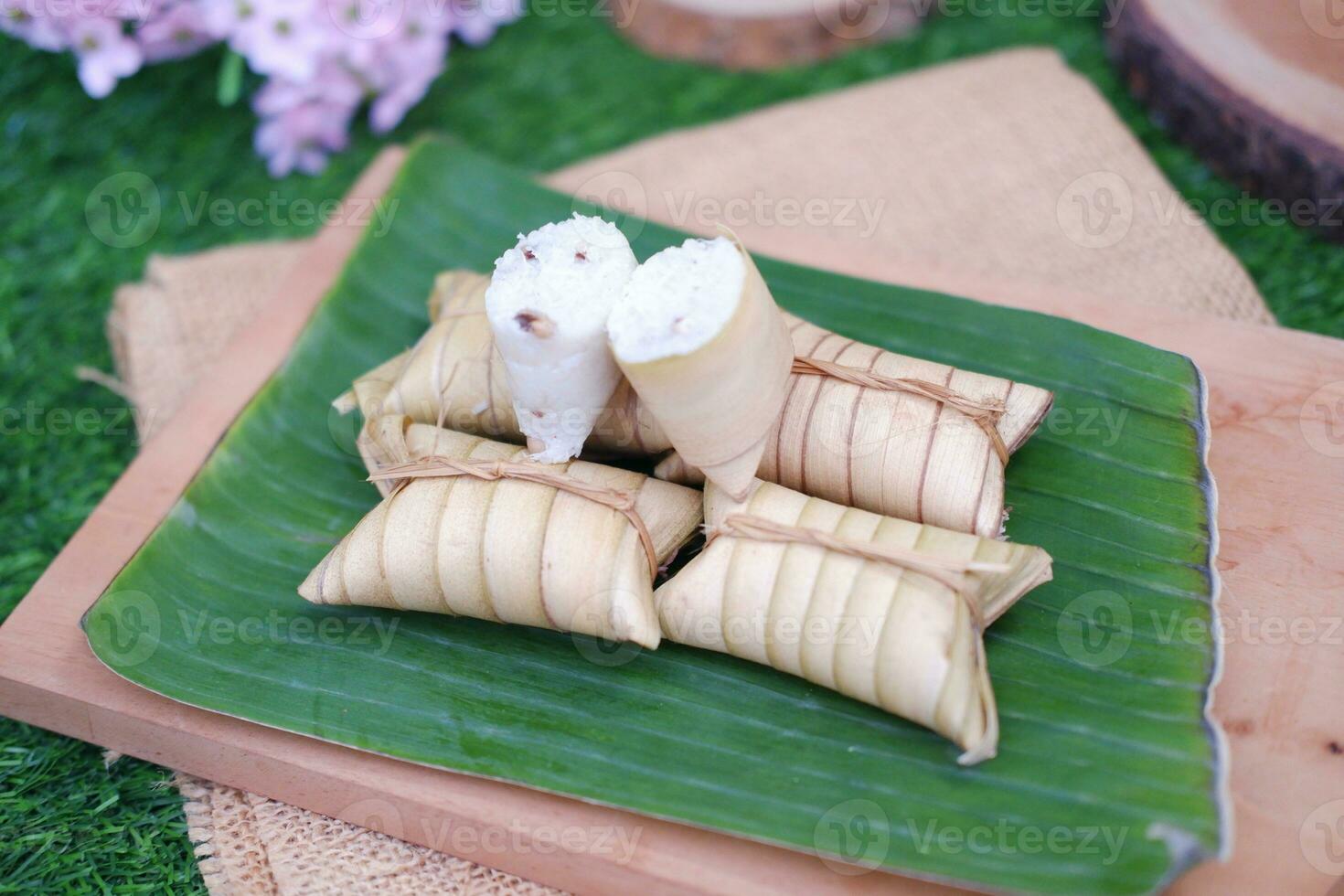 Lepet or Leupeut is a type of snack made from glutinous rice mixed with peanuts, cooked in coconut milk, then wrapped in coconut leaves. Close up view photo