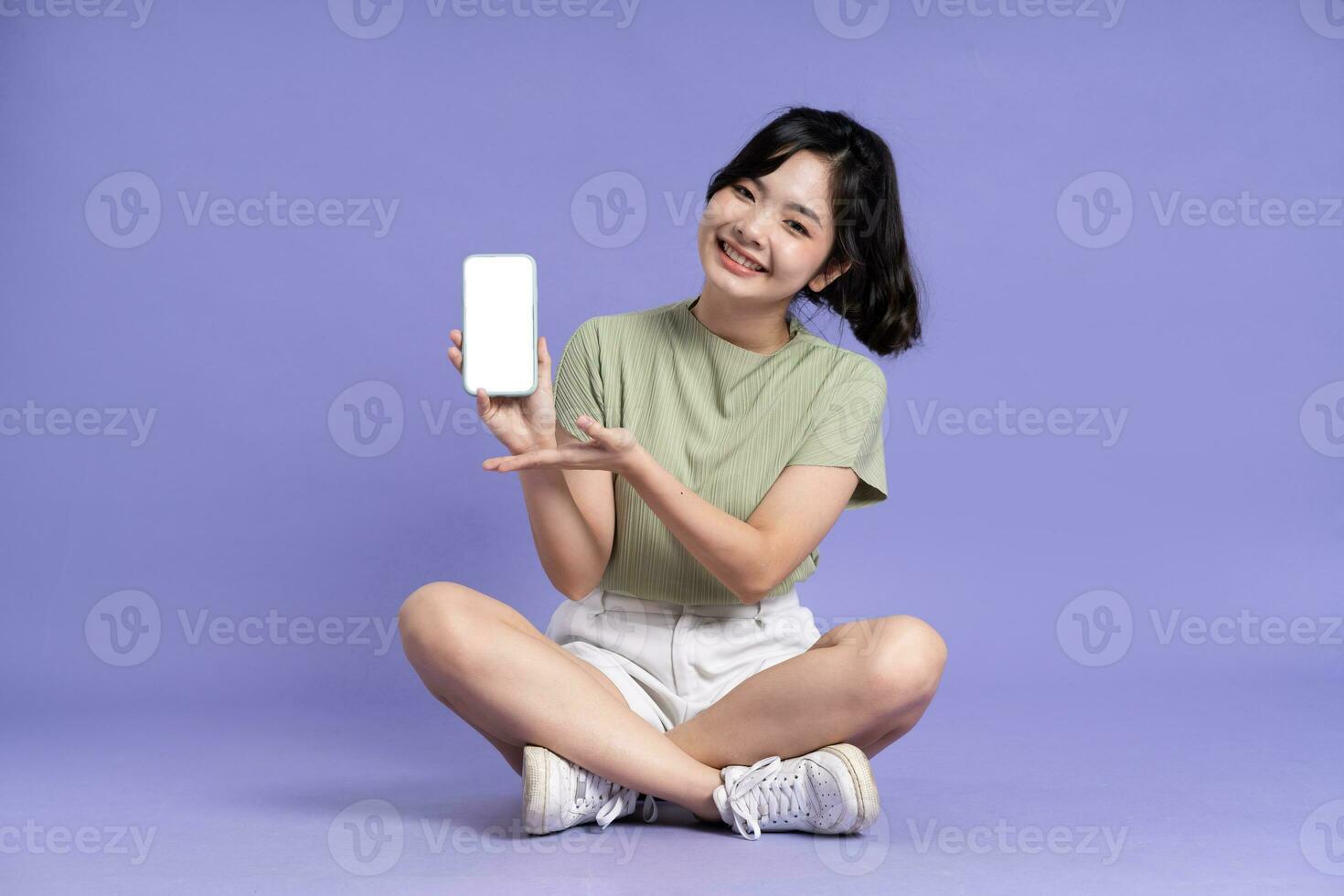 Portrait of beautiful asian girl sitting on purple background photo