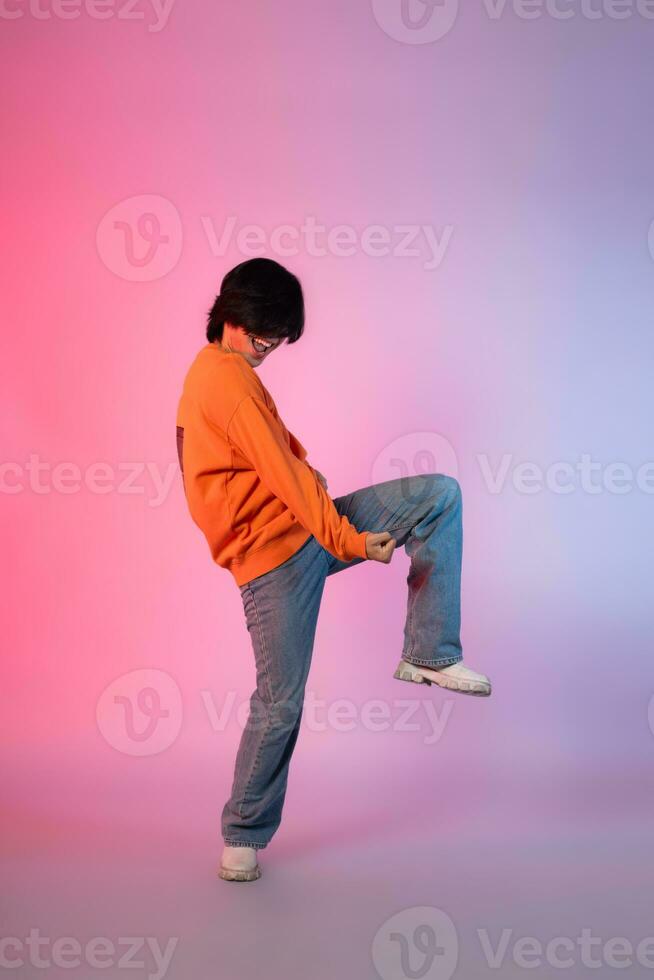 Image of a young Asian person dancing on a neon colored background photo