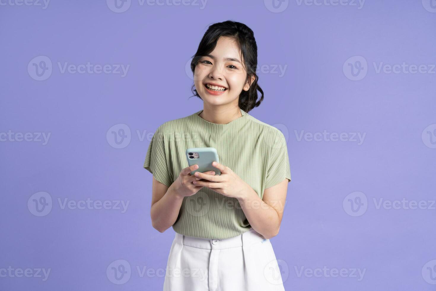 Portrait of beautiful asian woman using smartphone on purple background photo