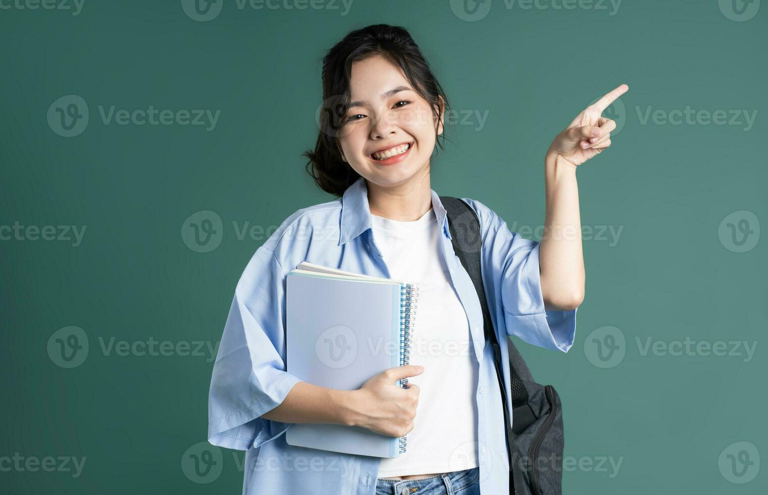 Portrait of a beautiful Asian student on a green background photo