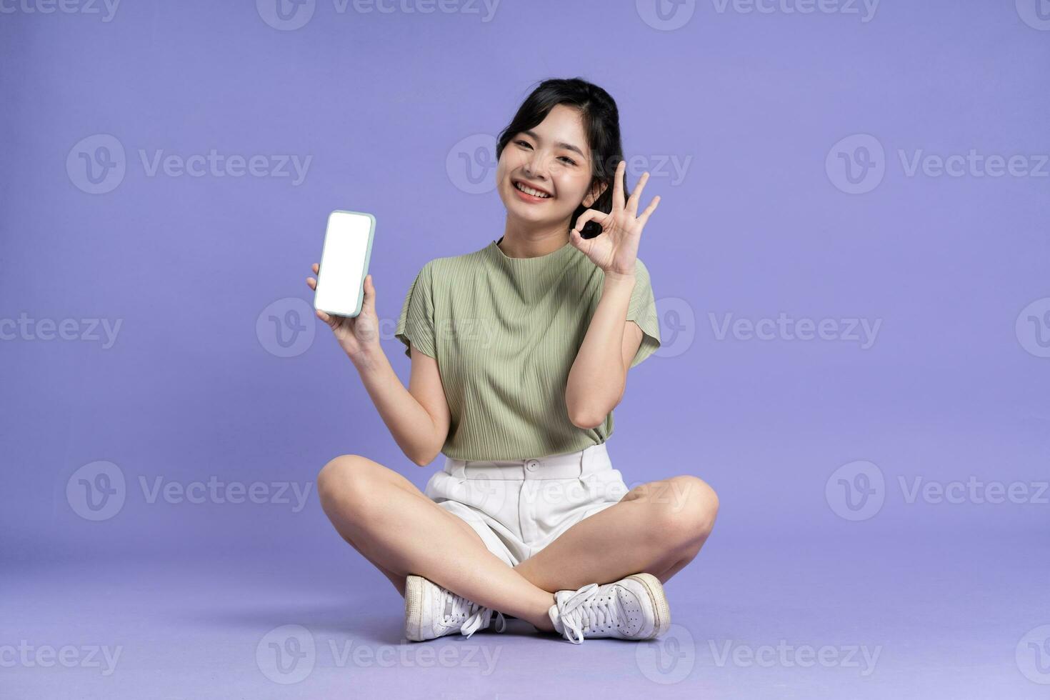 Portrait of beautiful asian girl sitting on purple background photo