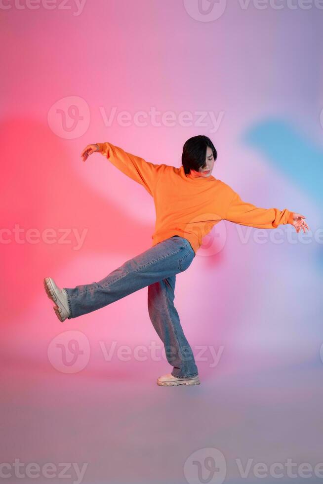 Image of a young Asian person dancing on a neon colored background photo