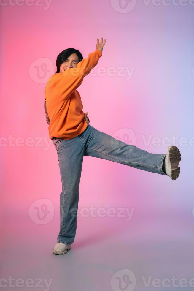 Image of a young Asian person dancing on a neon colored background photo