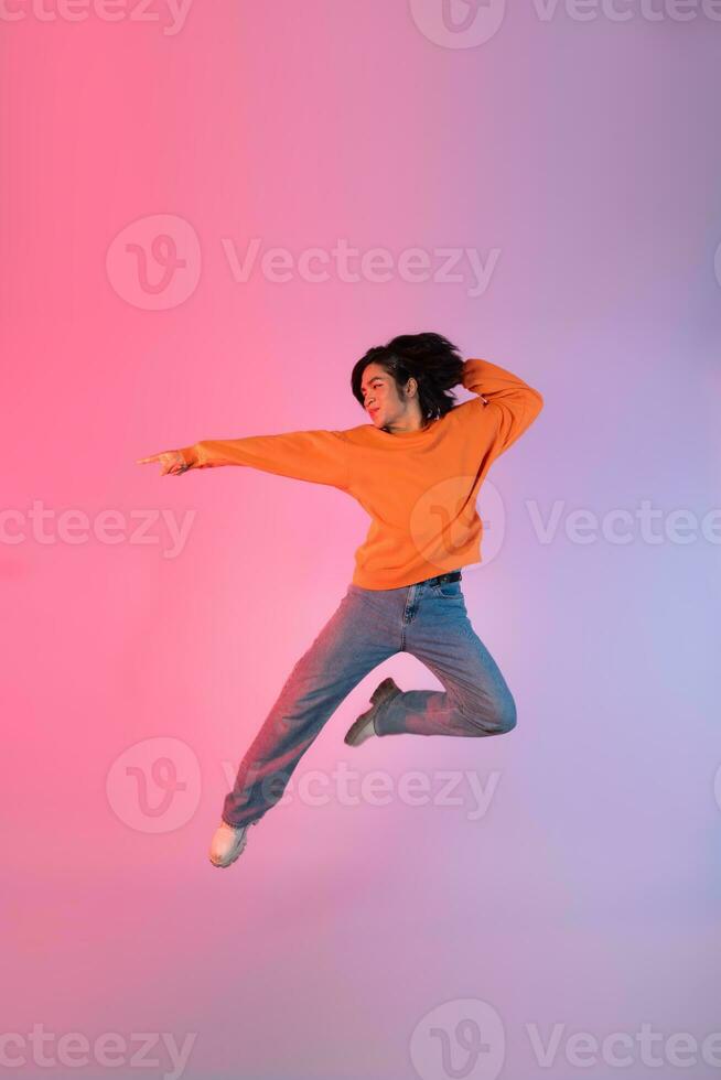 Image of a young Asian person dancing on a neon colored background photo