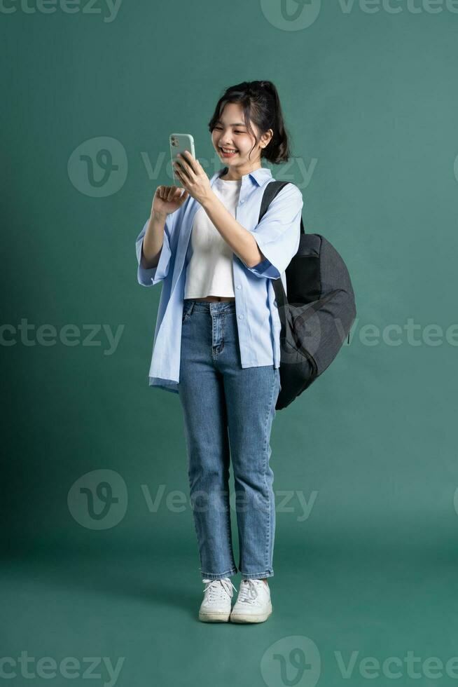 Portrait of a beautiful Asian student on a green background photo