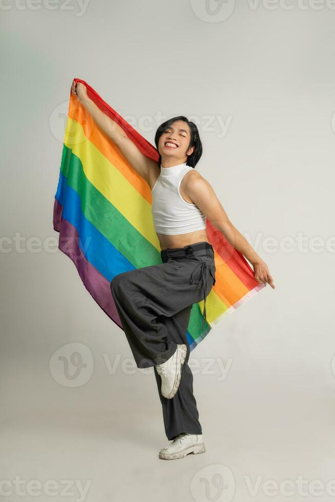 Image of Asian gay man holding a rainbow flag confidently posing on a white background photo