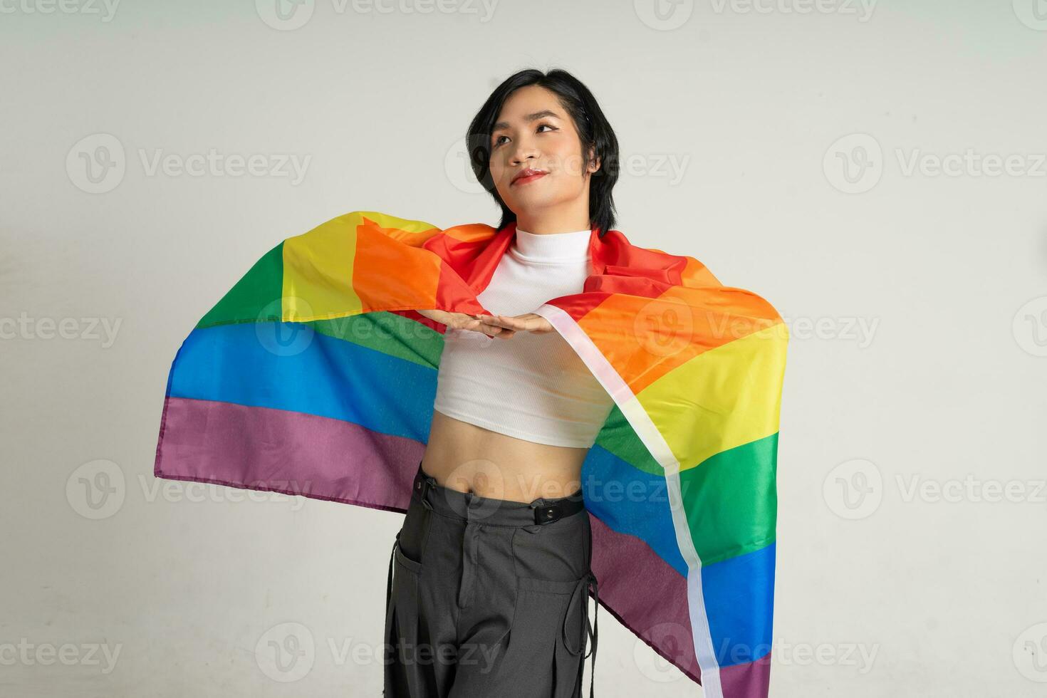 Image of Asian gay man holding a rainbow flag confidently posing on a white background photo