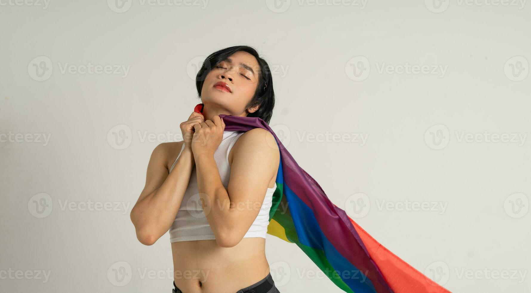 Image of Asian gay man holding a rainbow flag confidently posing on a white background photo