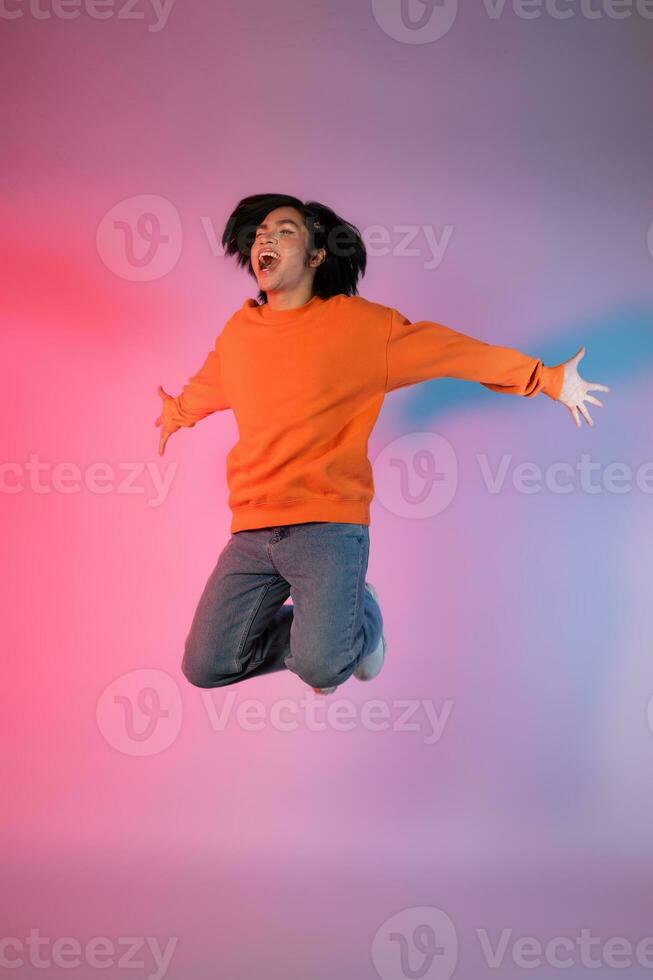 Image of a young Asian person dancing on a neon colored background photo