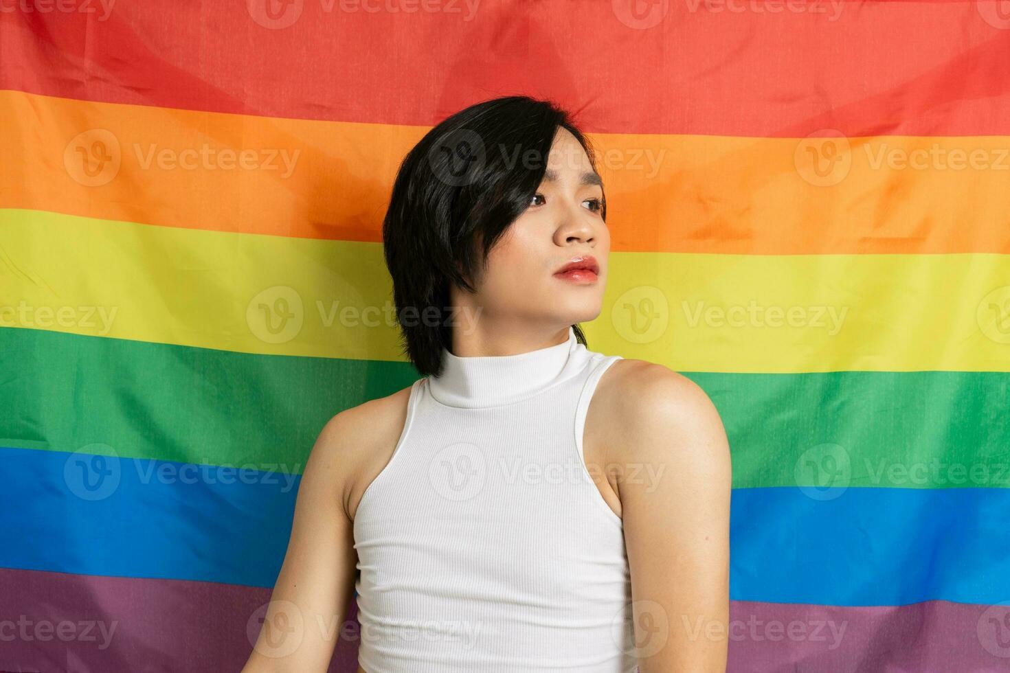 Image of Asian gay man holding a rainbow flag confidently posing on a white background photo