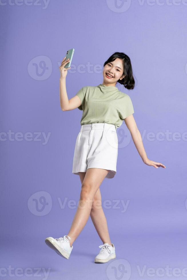 Portrait of beautiful Asian woman posing on purple background photo