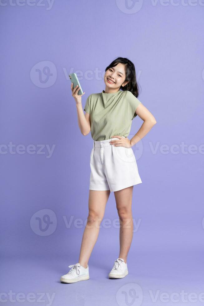 Portrait of beautiful Asian woman posing on purple background photo