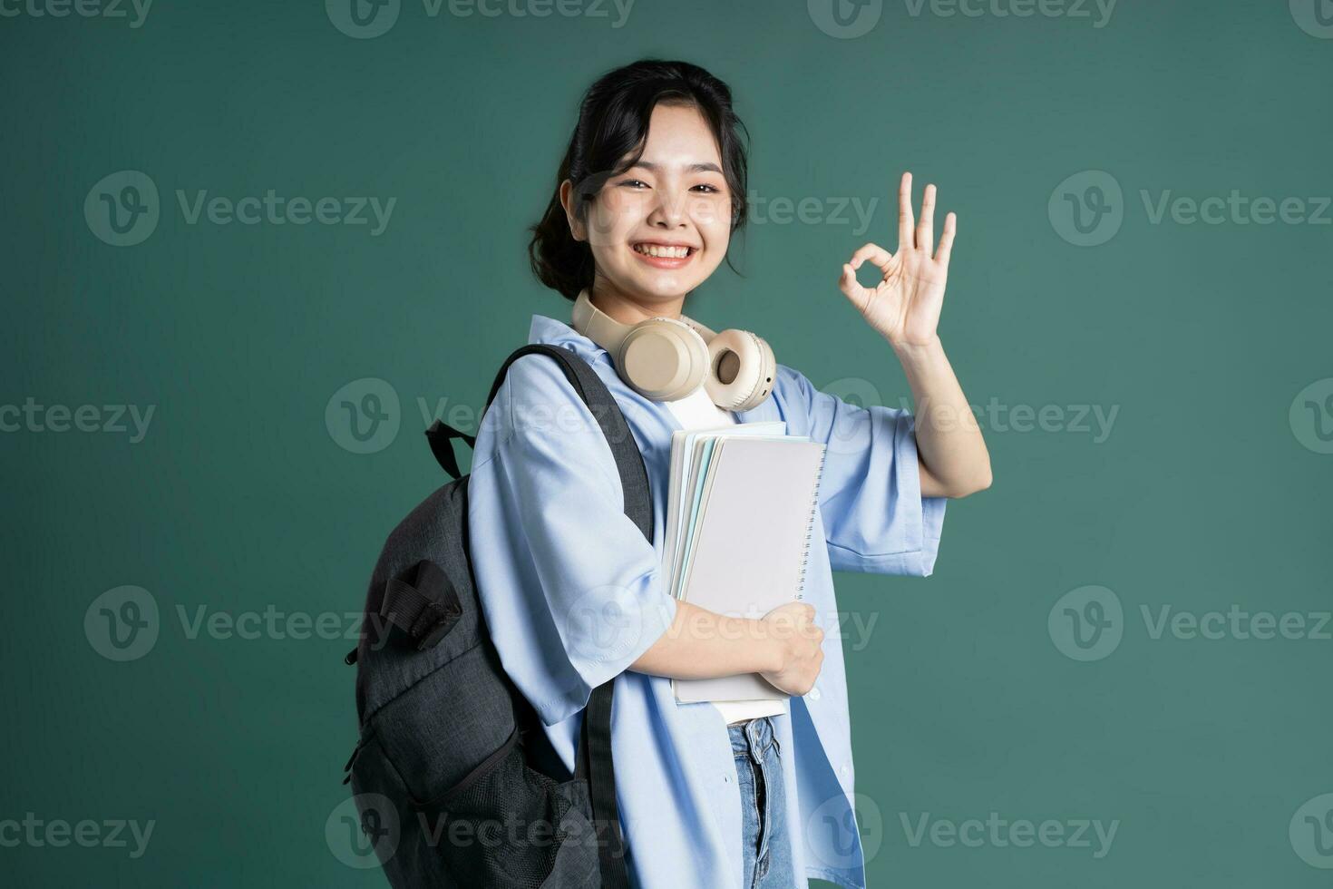 Portrait of a beautiful Asian student on a green background photo