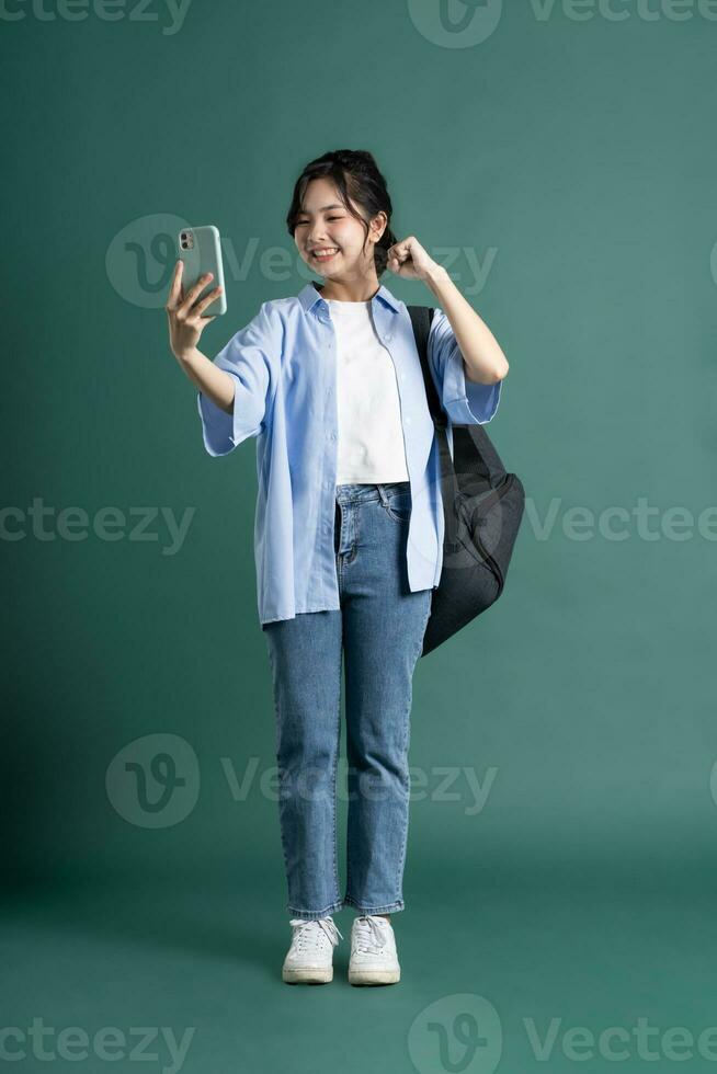 Portrait of a beautiful Asian student on a green background photo