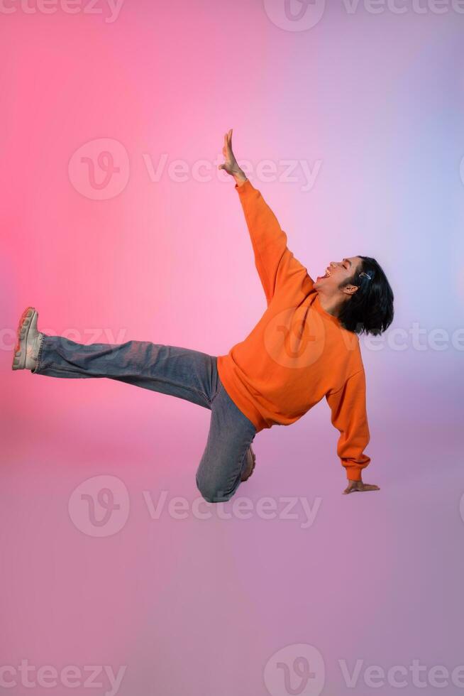 Image of a young Asian person dancing on a neon colored background photo