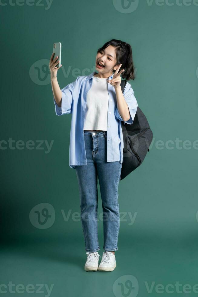 Portrait of a beautiful Asian student on a green background photo