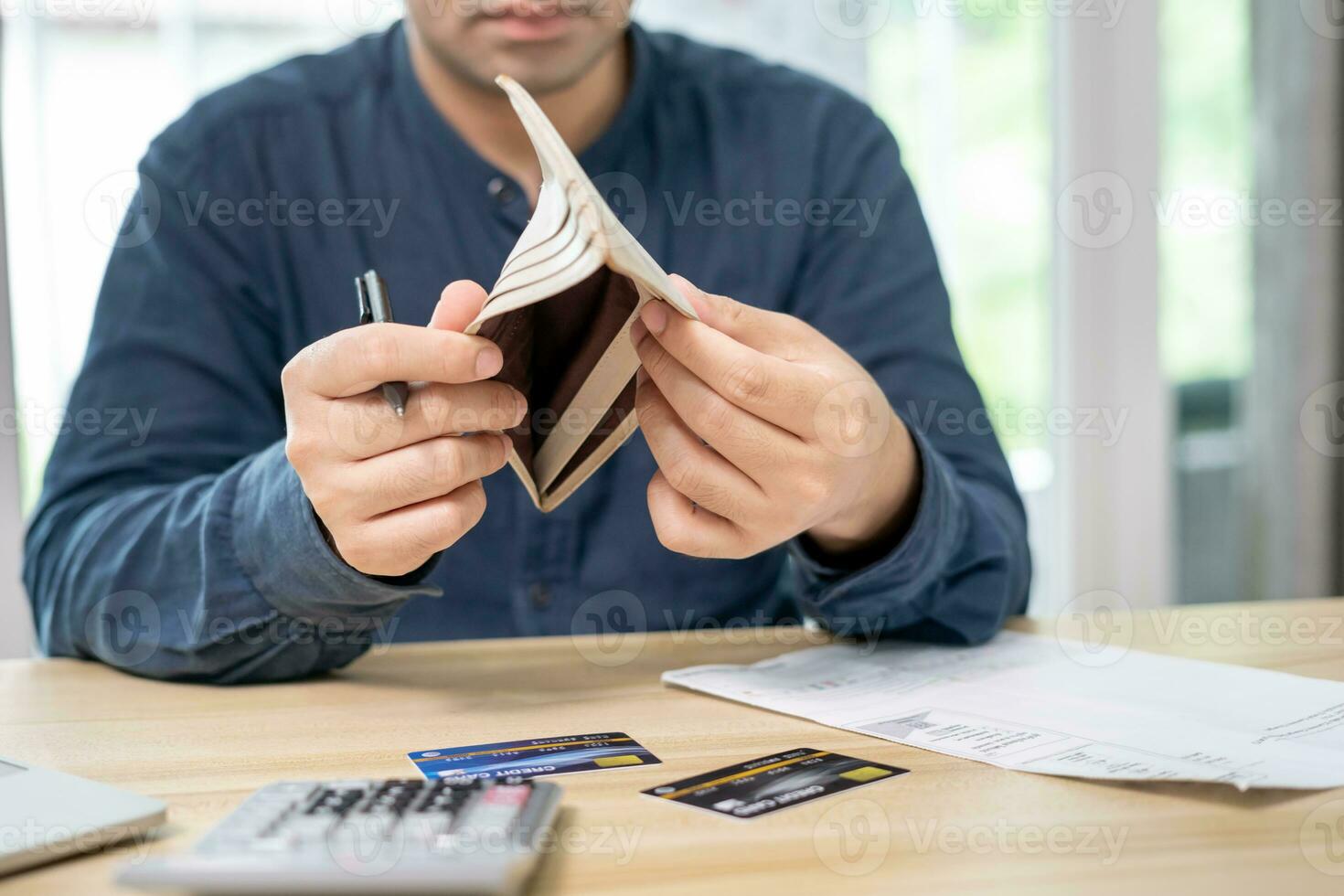 Stressed and headache asian man with large bills or invoices no money to pay to expenses and credit card debt. shortage, Financial problems, mortgage, loan, bankruptcy, bankrupt, poor, empty wallet photo