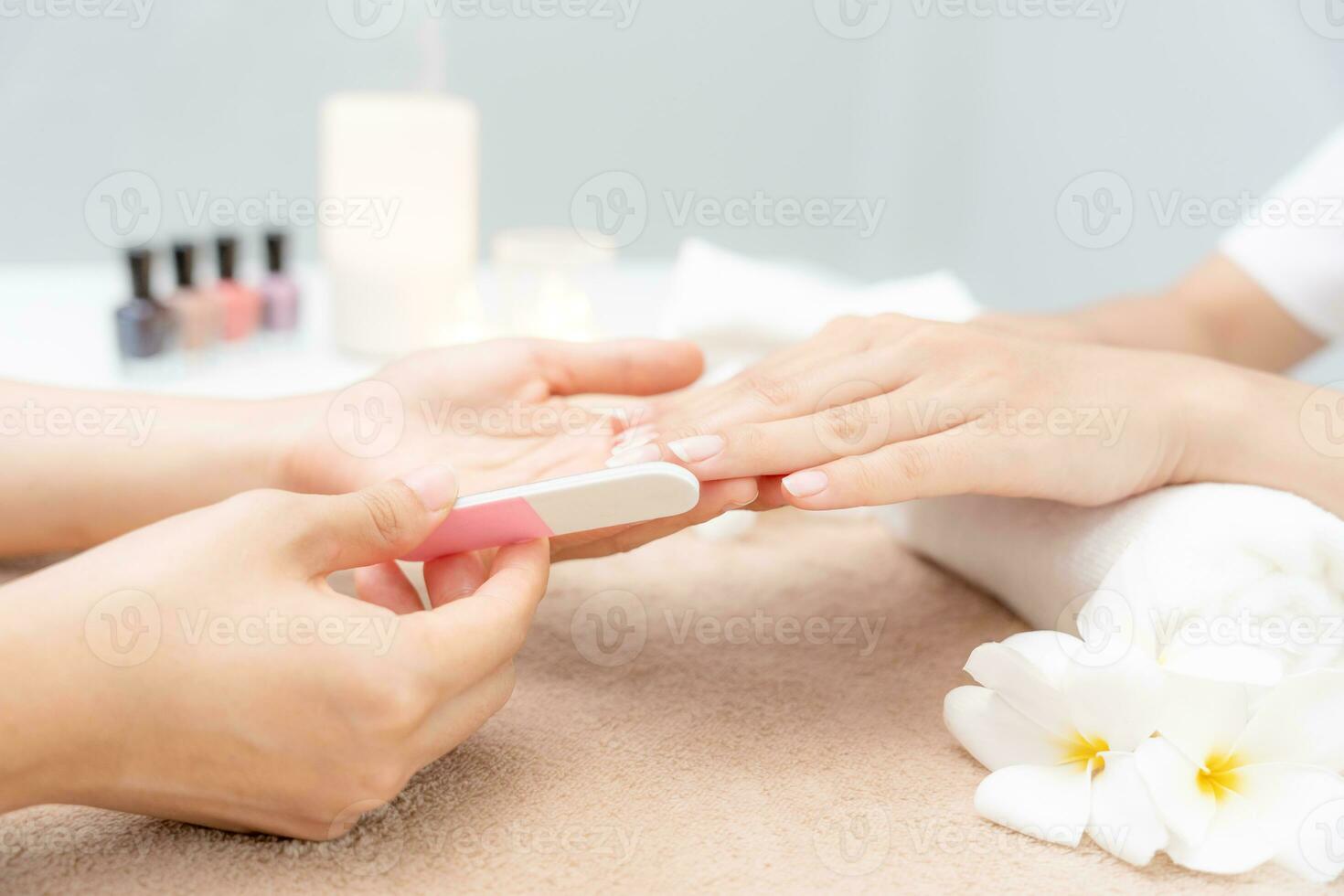 la mujer recibe el servicio de atención de la manicura esteticista profesional en el centro de spa. el salón de belleza de uñas usa una lima de uñas para el tratamiento de acristalamiento. manicurista hace que el cliente de uñas sea hermoso. tratamiento de spa para el cuidado del cuerpo foto