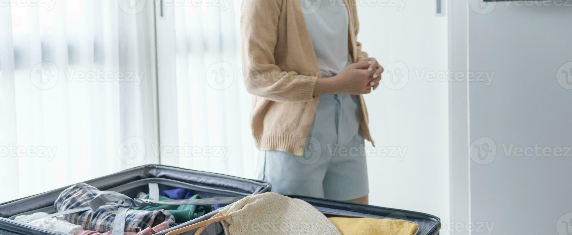 Asian girl preparing vacation choosing clothes with wardrobe in bedroom before holidays trip photo