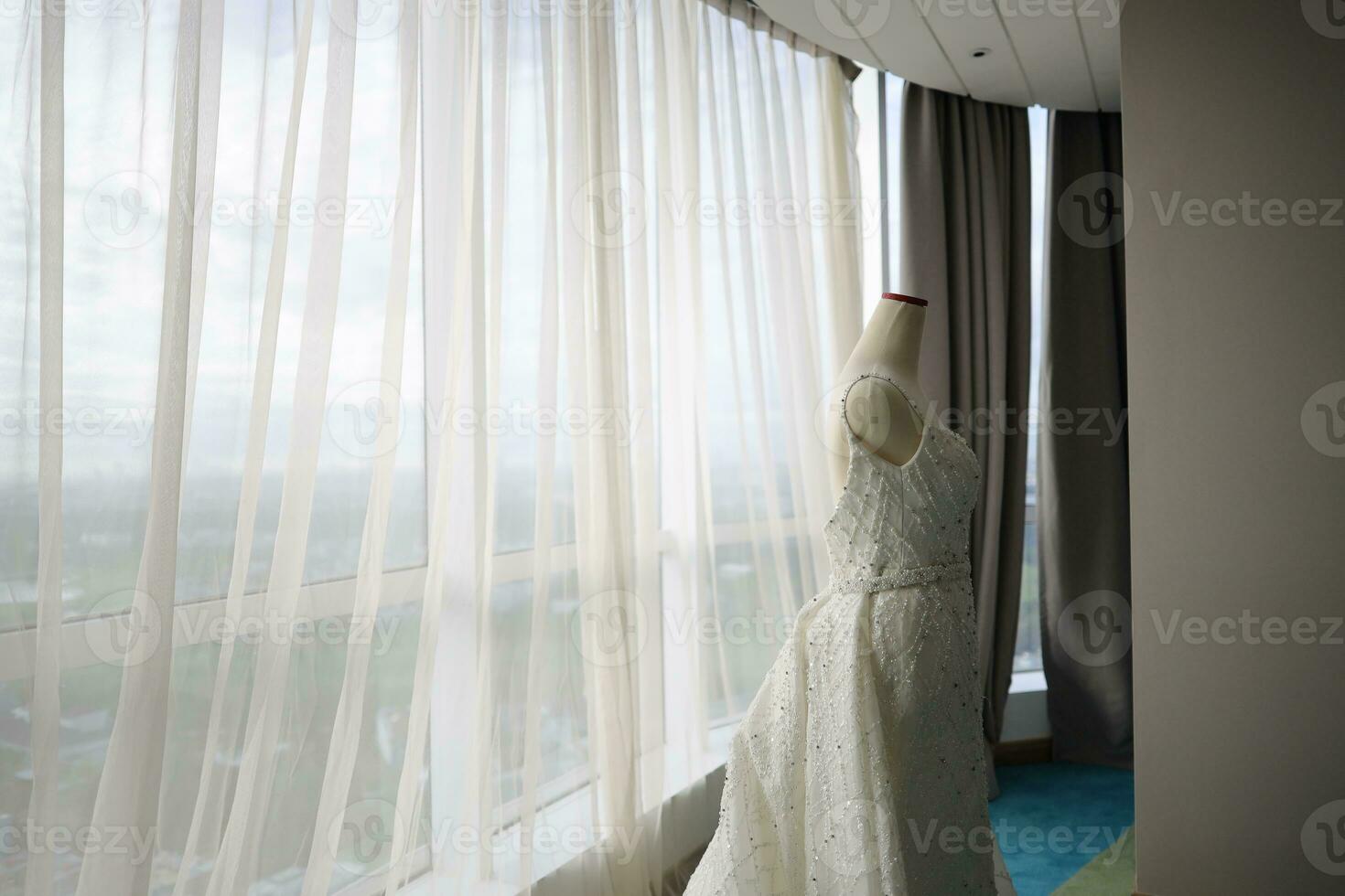 Beautiful White Wedding Dress on a White Mannequin in The Room With Large Window photo