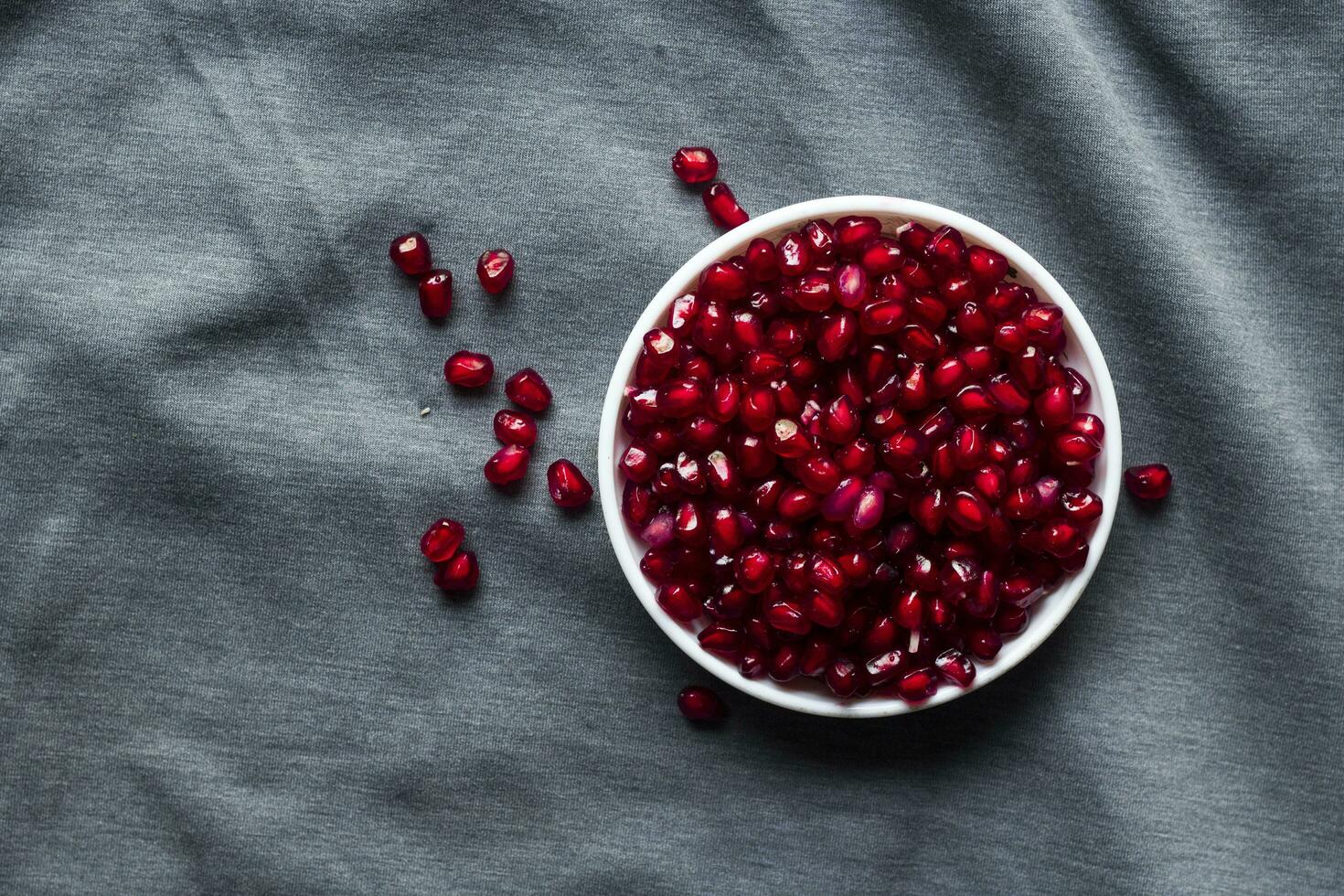 Ripe pomegranate seeds in a bowl on black background photo