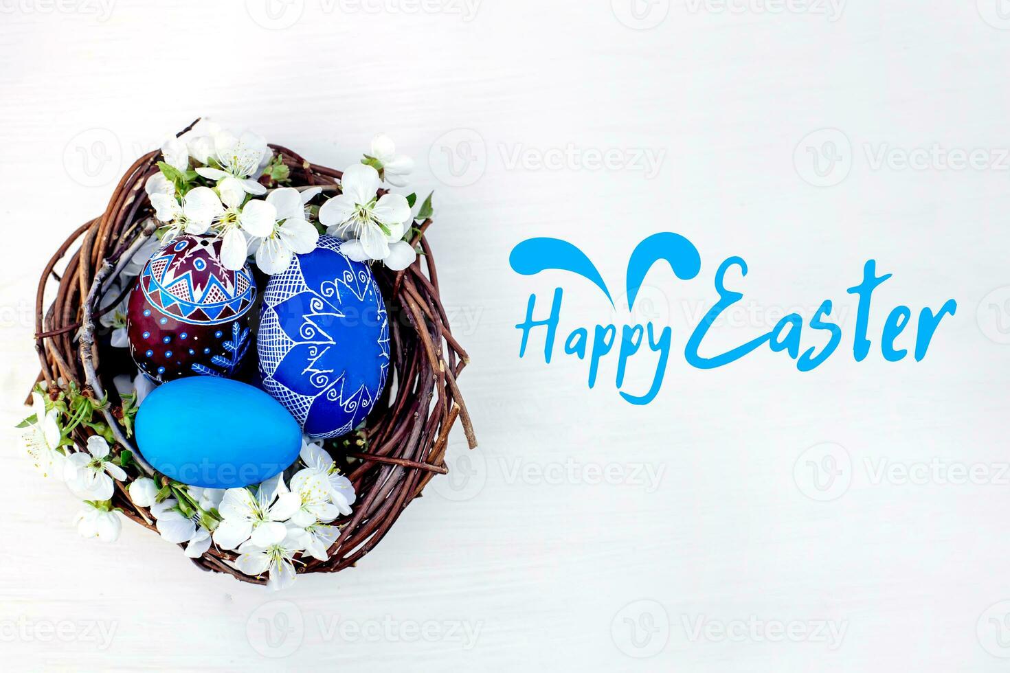 Text Happy Easter. nest with Easter eggs and branches of spring flowering cherries on a white wooden background. Rye eggs painted with natural dyes. photo