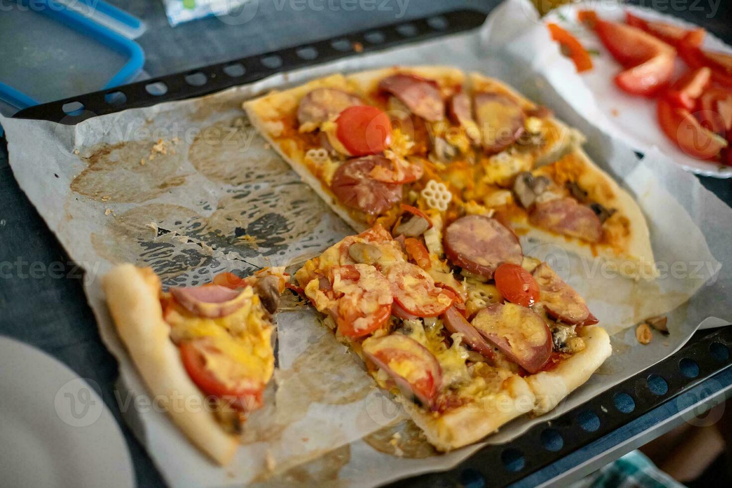 Remains of a sliced homemade pizza. Unfinished pizza on table at home. Pizza on baking. photo