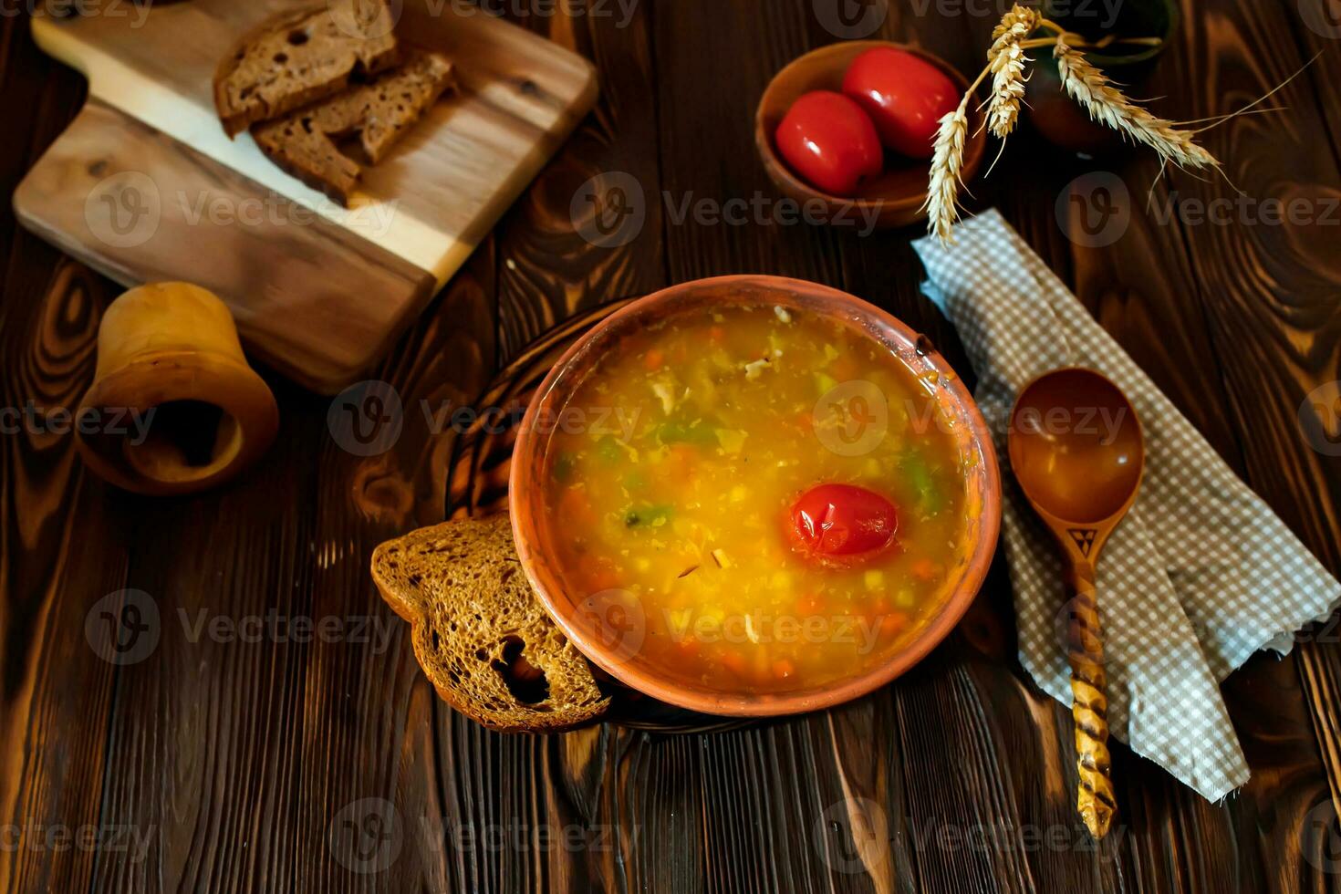 Tomato soup in a clay plate on a wooden vintage farm table near a piece of brown bread. photo