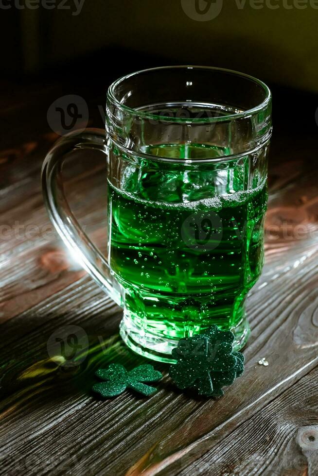 glass of beer at a party where they celebrate St. Patrick's Day. Brewed booze for an outdated Patrick's. Mug with green alcohol in a pub on a vintage wooden table. photo