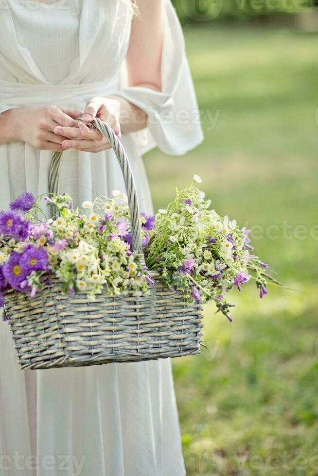 Girl with a basket of flowers. Chrysanthemums and daisies in a basket. photo