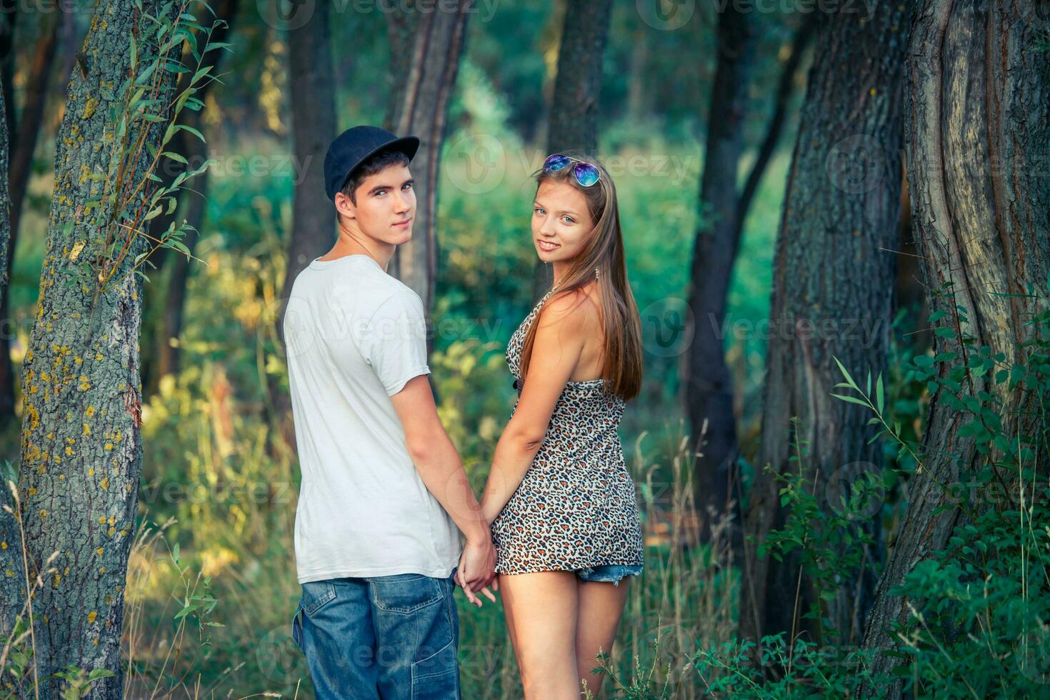 joven amoroso chico con un niña participación manos. el chico y el niña convertido alrededor, entrando el bosque. foto