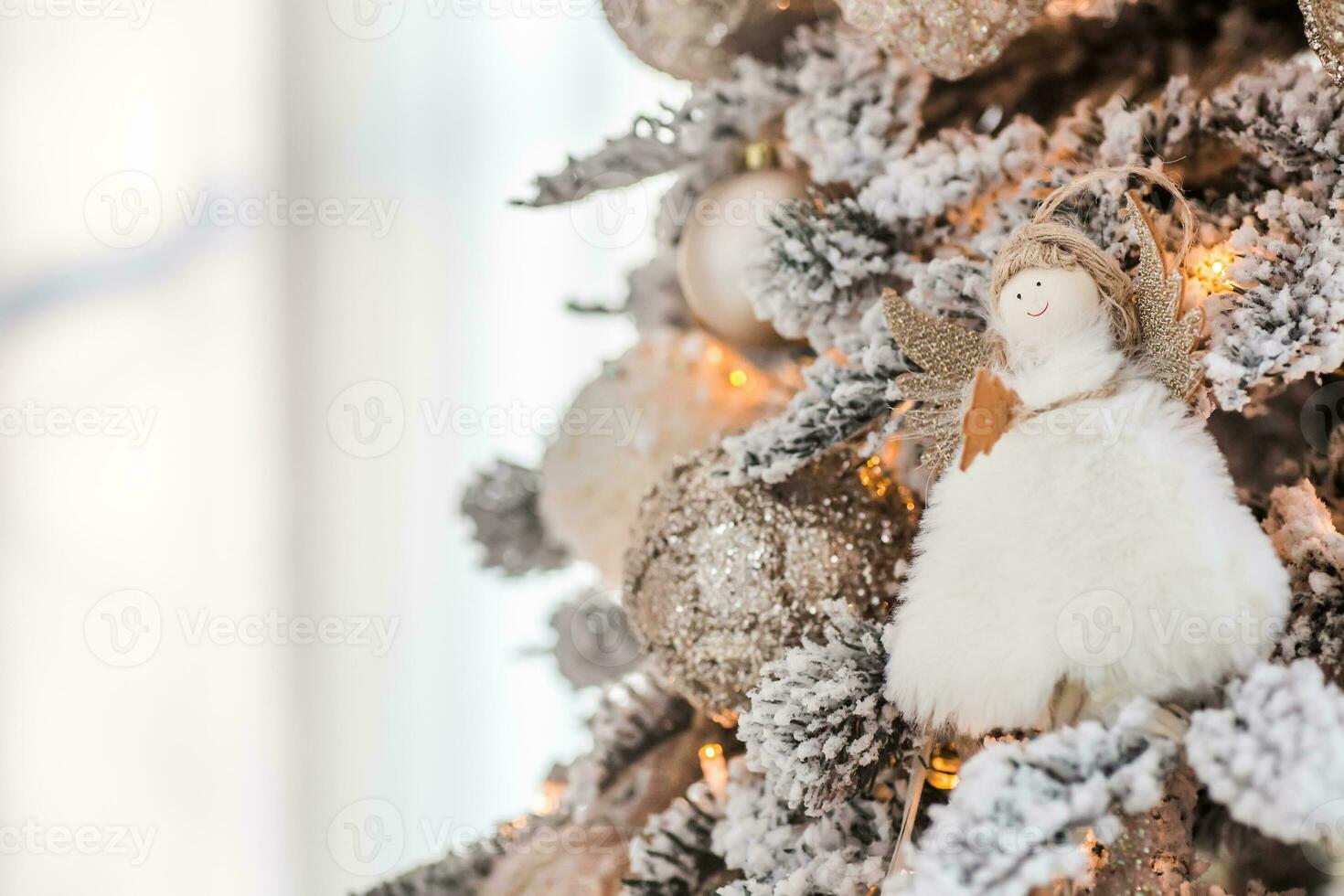 A Christmas angel on the branches of a Christmas tree against the background of a clock showing 12. New Year's Eve 2022 Celebration photo