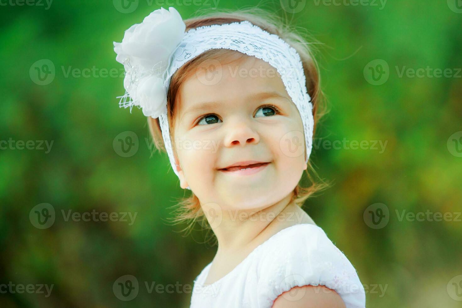 retrato de un hermosa niña en un blanco cordón venda con un grande flor. foto