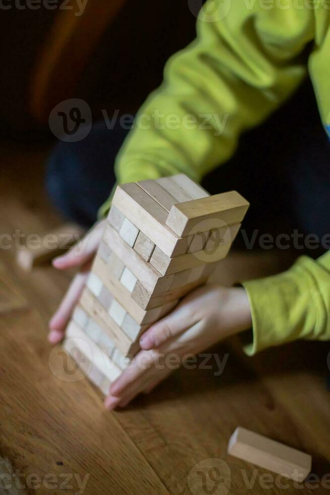 The child builds a tower of wooden blocks. Soft focus photo