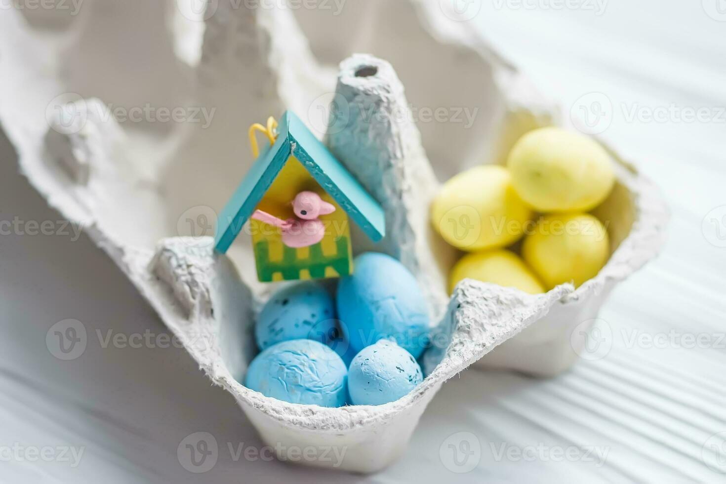 A bunch of yellow and blue eggs in egg carton. near the house with a bird. The concept of an abandoned home of Ukraine for the Easter holiday. photo