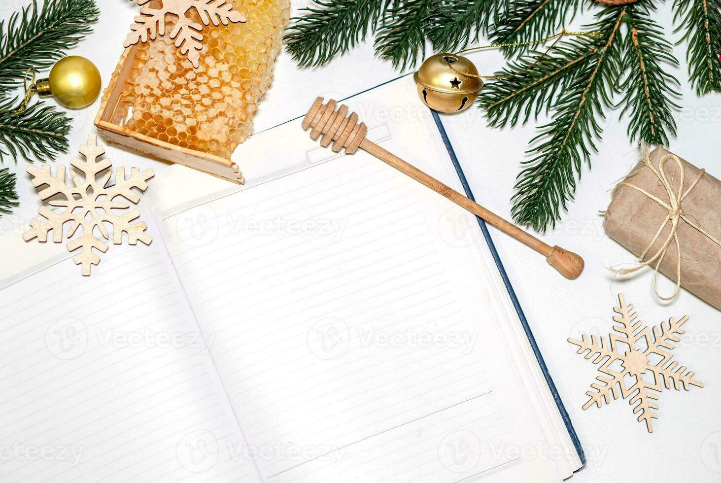 Cellular honey in wooden frame near empty notebook for records. Christmas background with branches of New Year's spruce, golden balls and snowflakes, face mask photo